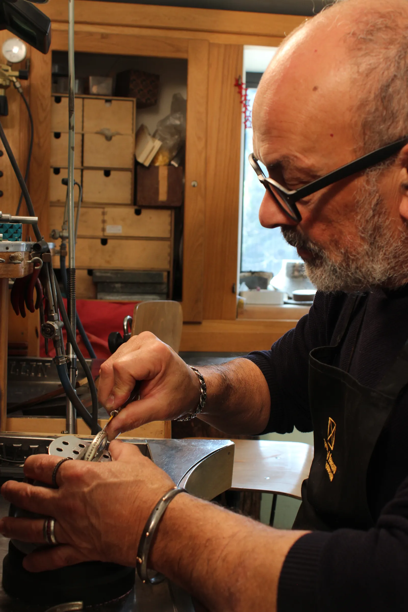 Paolo Del Ferraro al banco del suo laboratorio di Velletri mentre lavora un anello con le pinze