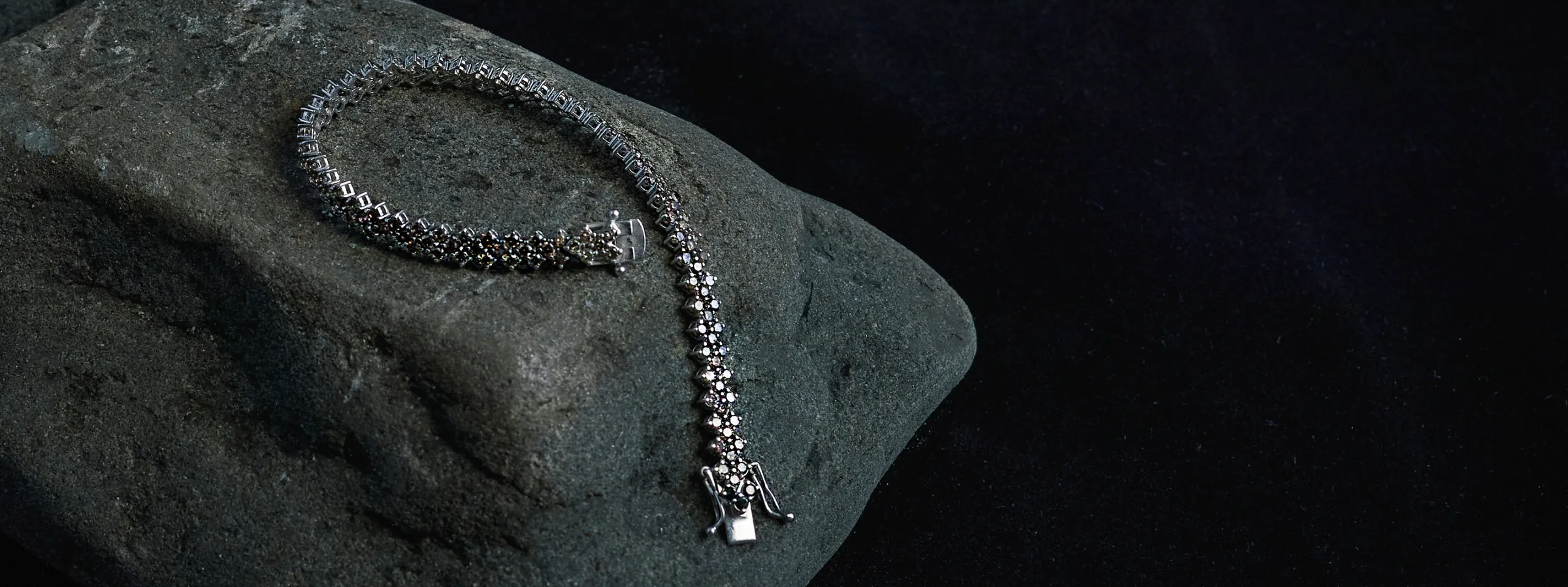 Bracciale tennis Celestial Bodies con pietre incastonate su una roccia scura