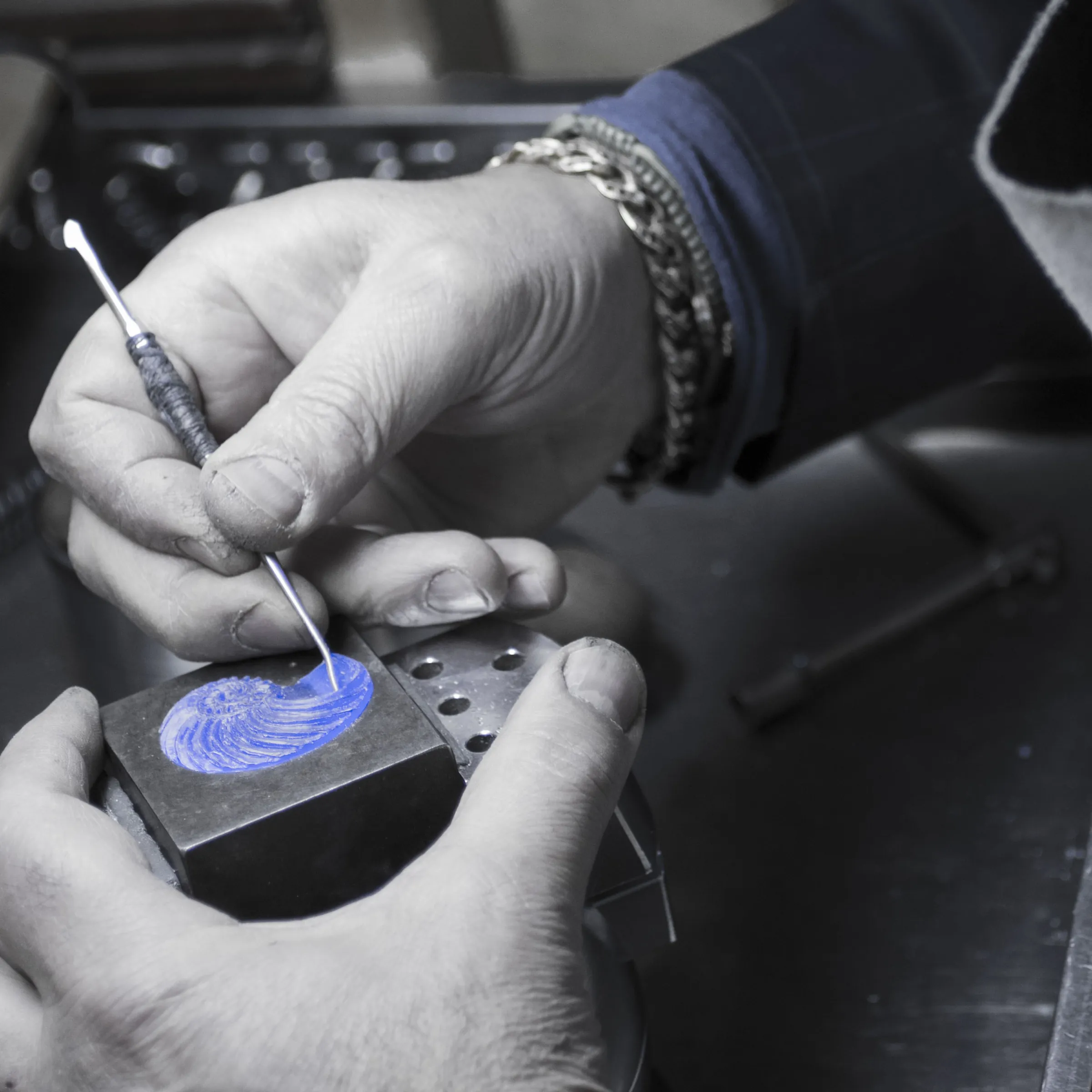 Dettaglio delle mani che intagliano un modello in cera blu, foto in bianco e nero